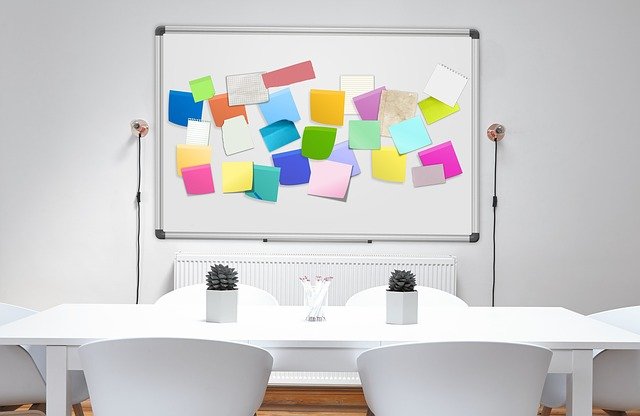 Imagem de mesa de reunião com quadro banco repleto de post-its